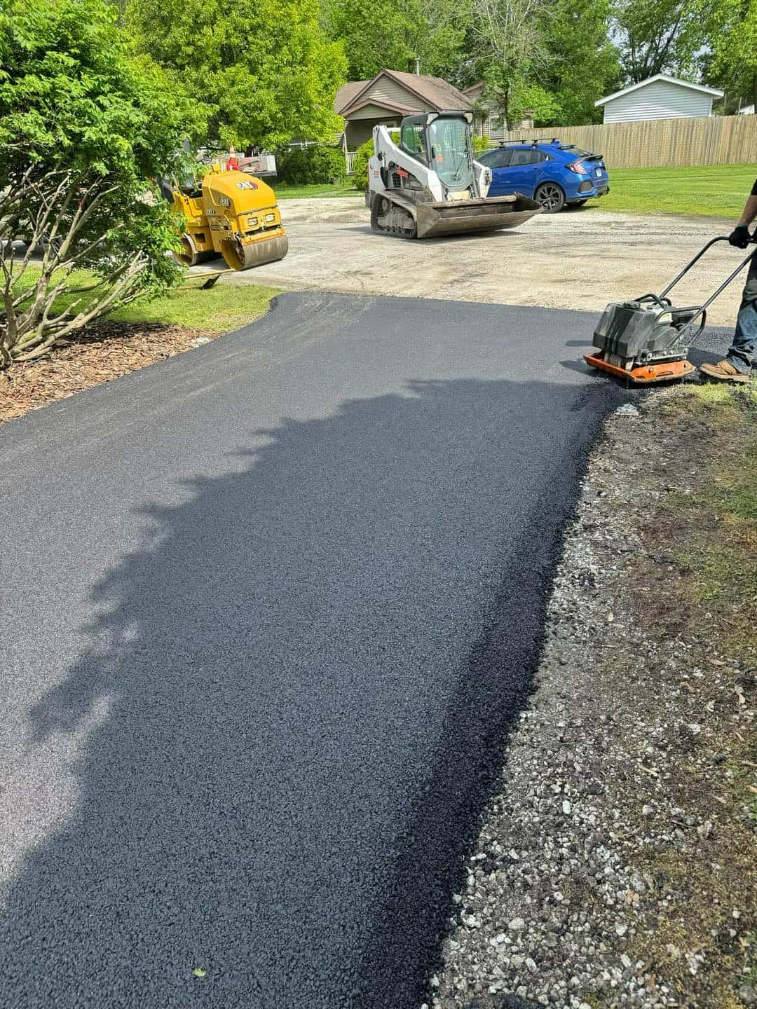 Plate compactor finishing a fresh asphalt driveway